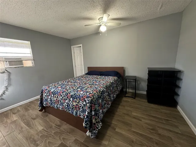 a bedroom with a bed and a dresser with wooden floor