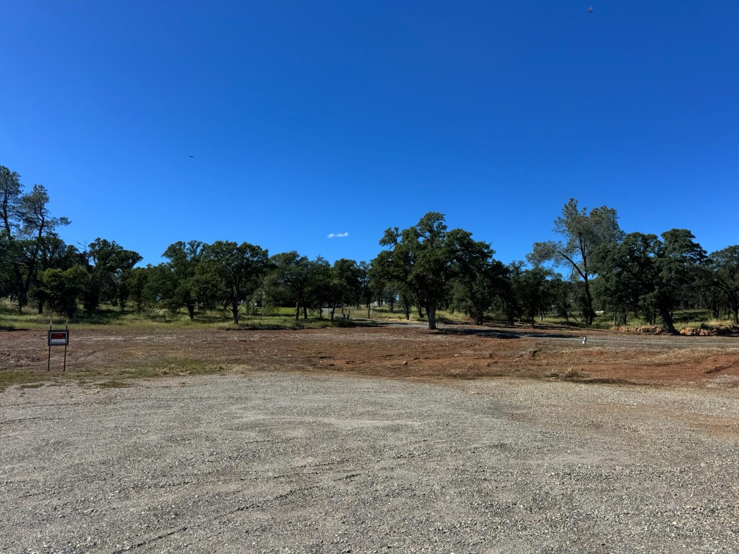 a view of dirt field with trees in background