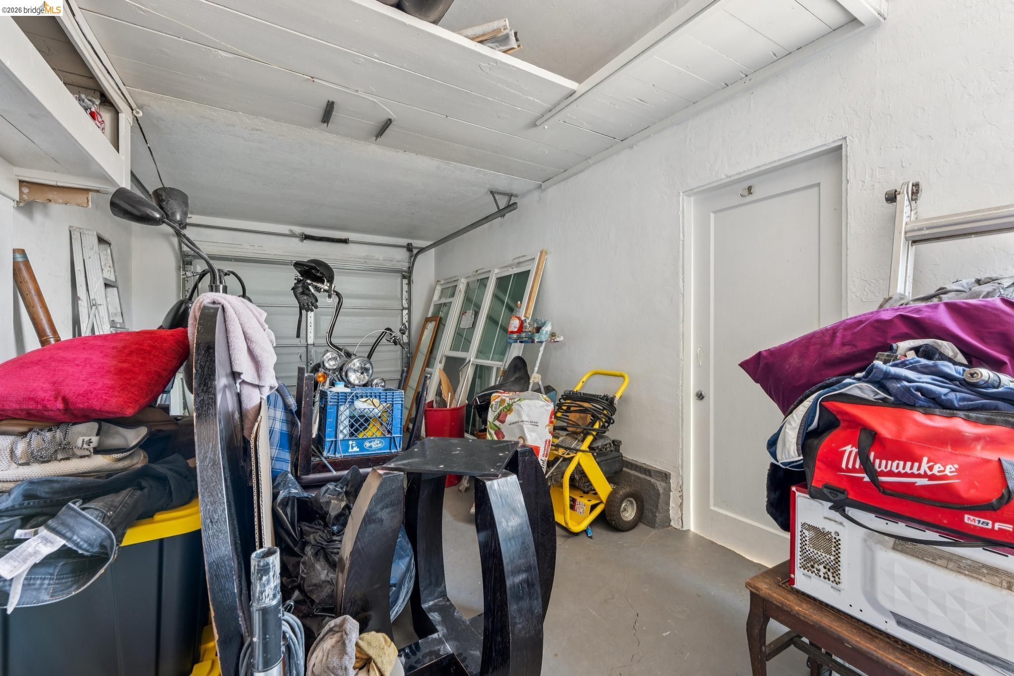 2879 Rheem Avenue Richmond, CA 94804 - Photo 44 of 45 Interior garage space featuring a roll-up garage door, painted concrete flooring, and a white paneled door