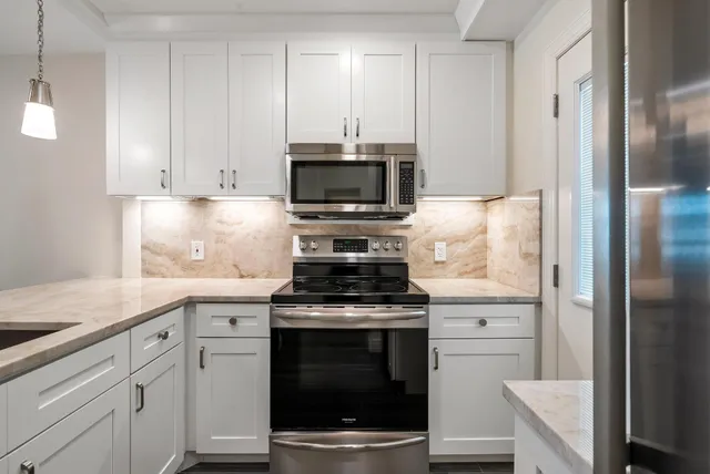 a kitchen with cabinets stainless steel appliances and wooden floor