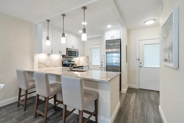 a kitchen with kitchen island granite countertop a table chairs refrigerator and microwave