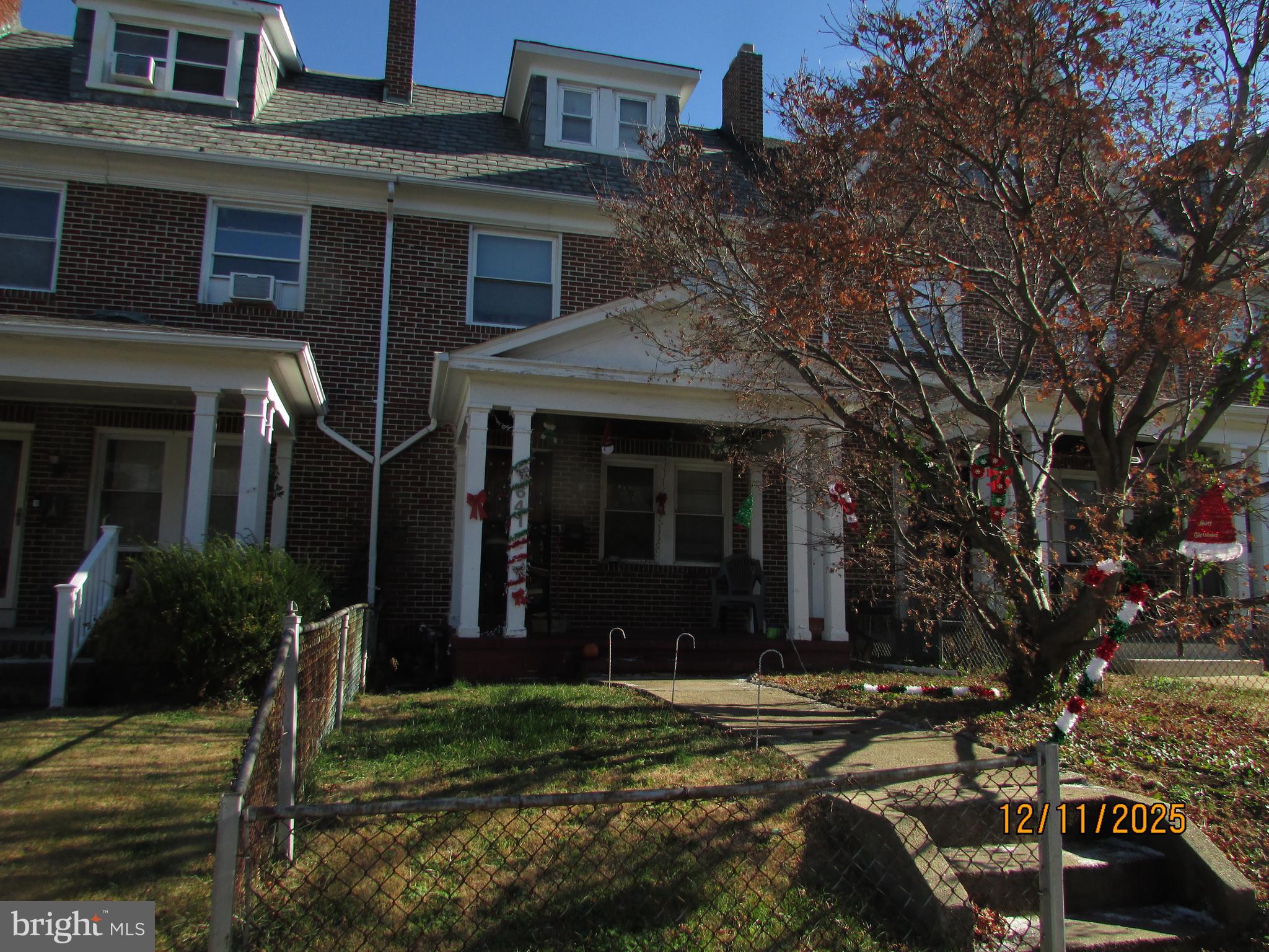 a view of a house with brick walls plants and large tree