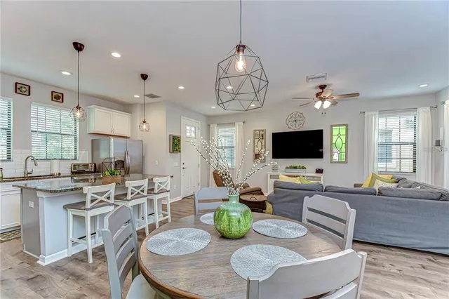 a kitchen with granite countertop a center island a refrigerator a stove a dining table and chairs