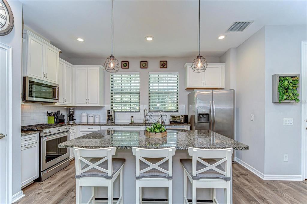 5703 Colony Glen Road Lithia, FL 33547 - Photo 8 of 53 a kitchen with stainless steel appliances granite countertop a stove a refrigerator a sink a dining table and chairs with wooden floor