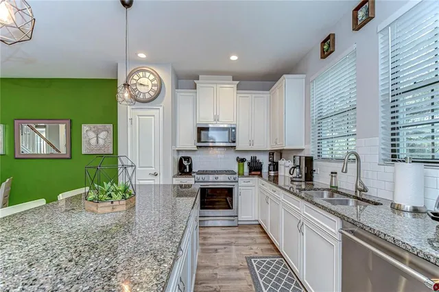 a view of a kitchen with granite countertop stainless steel appliances a stove center island a stove cabinets a rug and a window