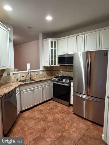 a kitchen with granite countertop a refrigerator stove and sink