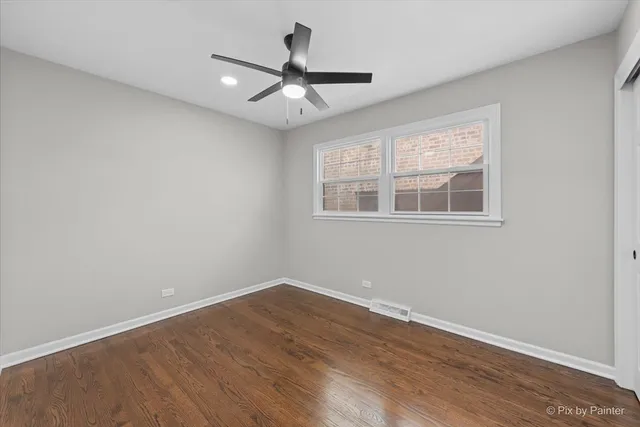 an empty room with wooden floor fan and windows