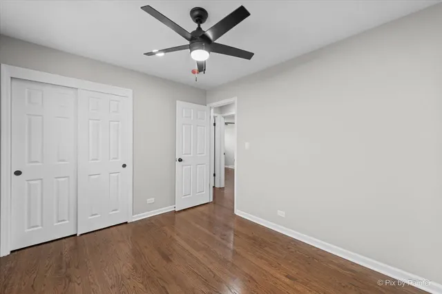 an empty room with wooden floor and ceiling fan