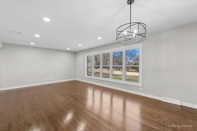 a view of an empty room with wooden floor and windows