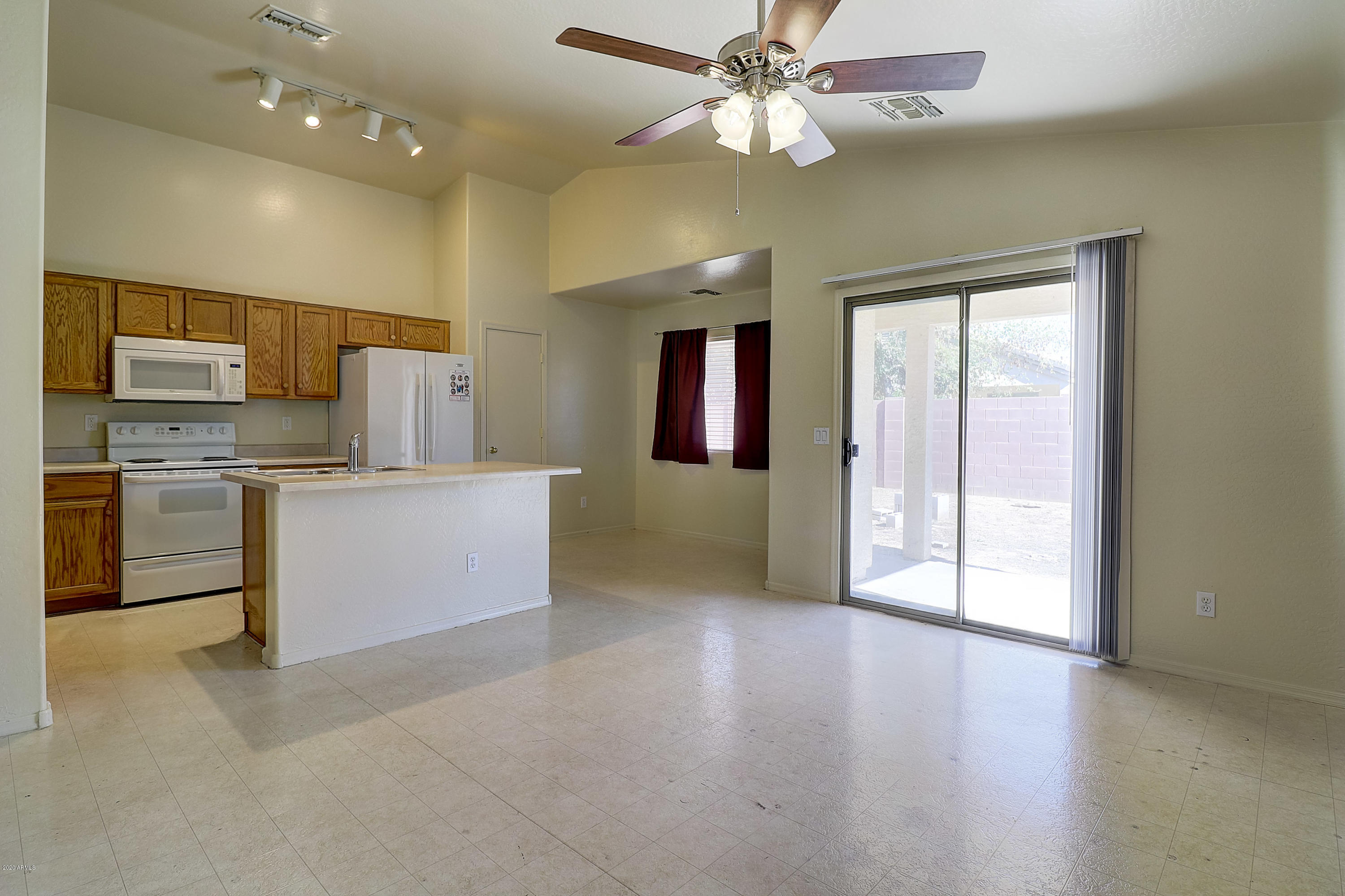 8461 West Riley Road Tolleson, AZ 85353 - Photo 10 of 25 a view of a kitchen with a stove cabinets a ceiling fan and wooden floor