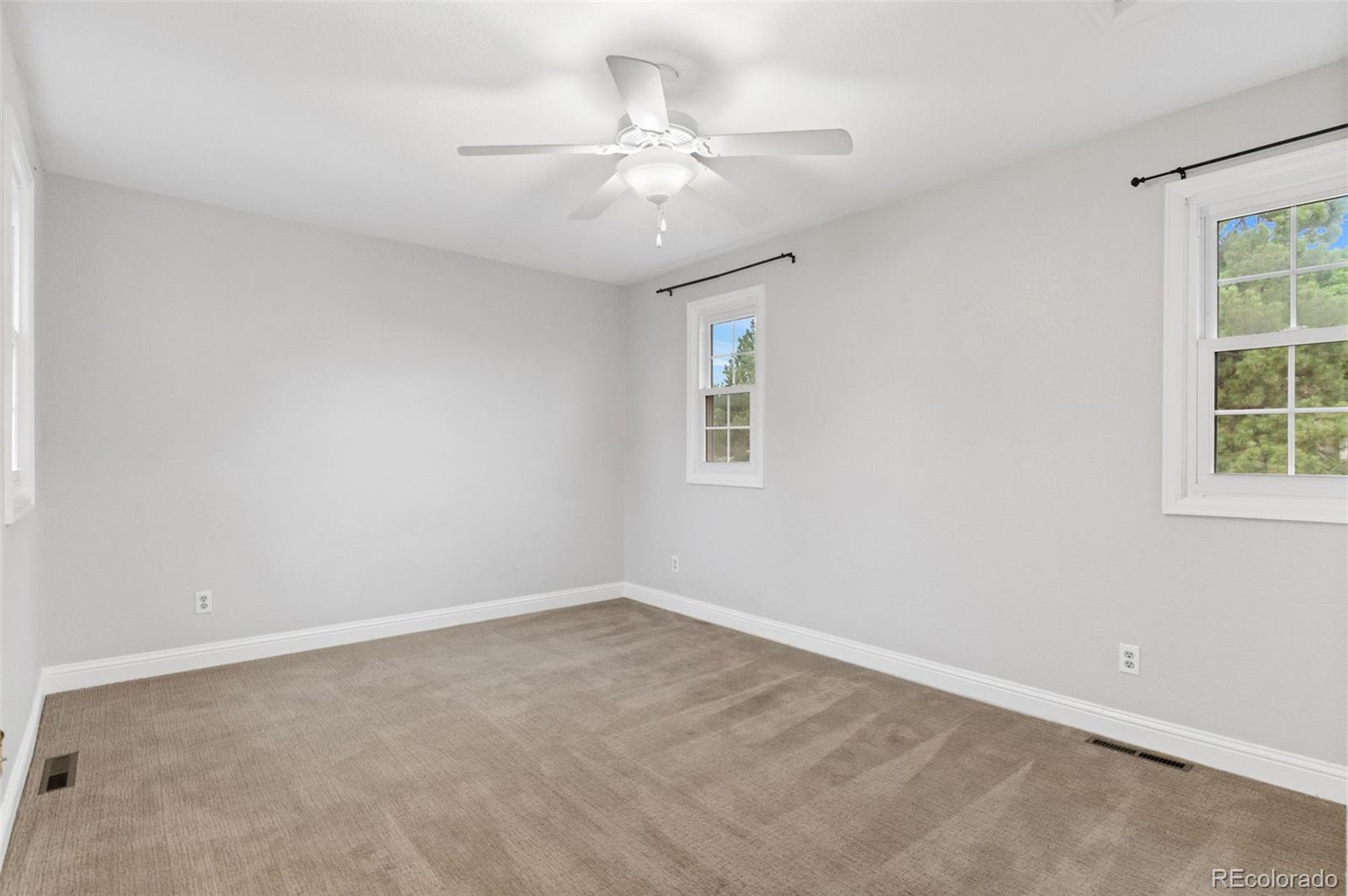 8385 Sweet Water Road Lone Tree, CO 80124 - Photo 31 of 50 an empty room with a chandelier fan and windows