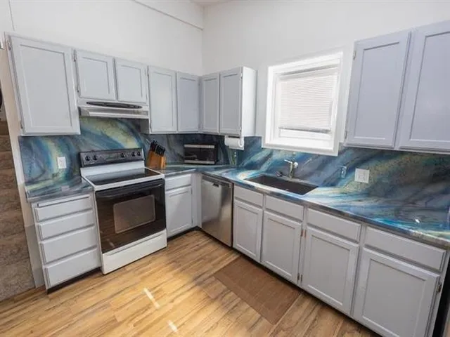 a kitchen with granite countertop white cabinets and stainless steel appliances