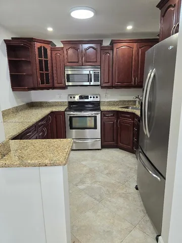 a kitchen with stainless steel appliances granite countertop a refrigerator stove and sink