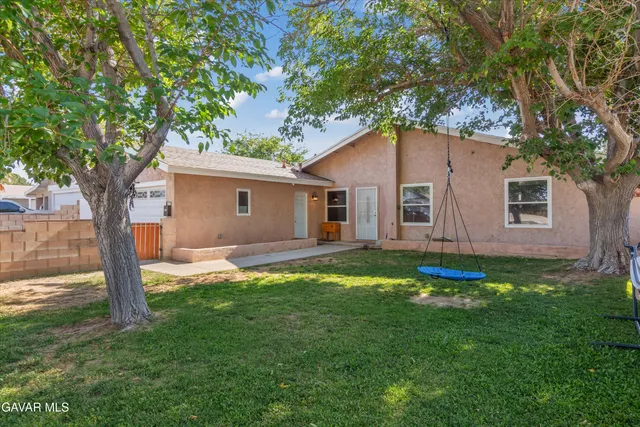 a backyard of a house with plants and large tree