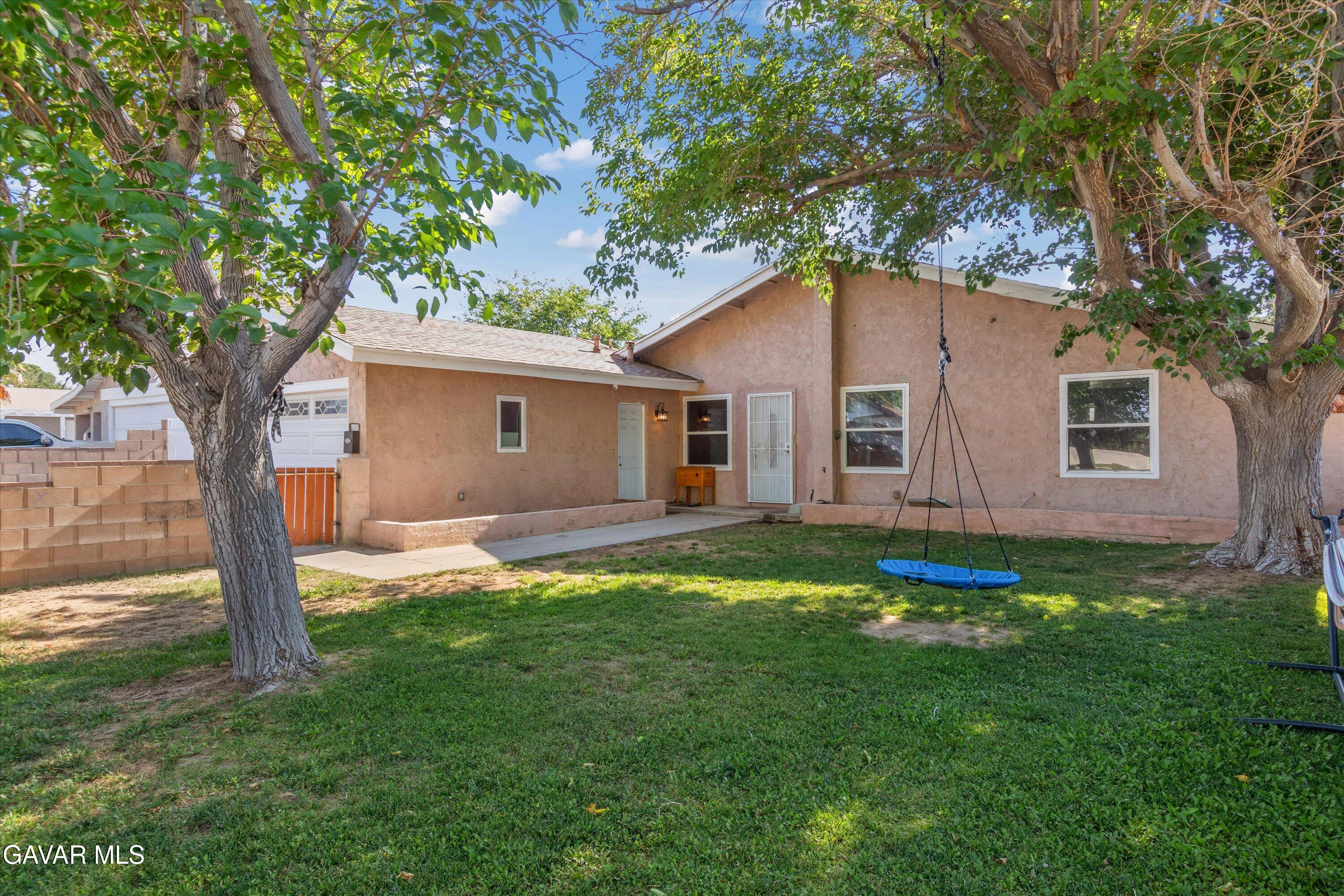 a backyard of a house with plants and large tree
