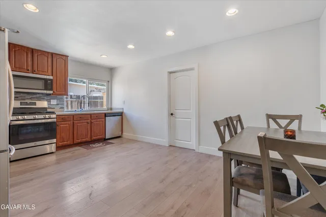 a living room with stainless steel appliances furniture and a kitchen view