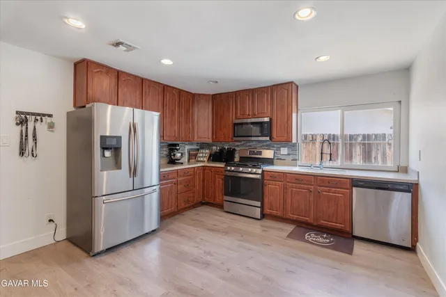 a kitchen with stainless steel appliances granite countertop a refrigerator stove a sink and dishwasher with wooden floor
