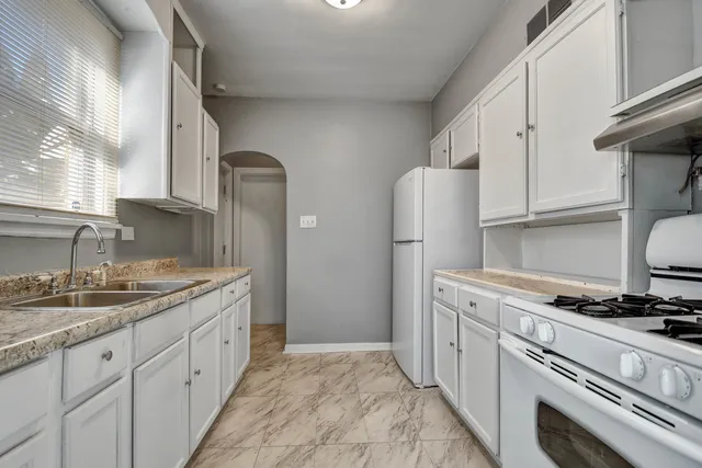 a kitchen with granite countertop a sink stove and refrigerator