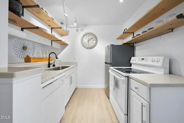 a kitchen with white cabinets and clock on the wall
