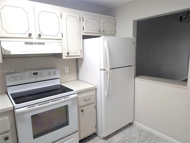 a white refrigerator freezer and a stove sitting inside of a kitchen