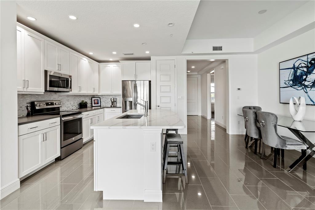 10520 Boardwalk Loop, Unit 302 Bradenton, FL 34202 - Photo 11 of 45 a kitchen with stainless steel appliances kitchen island granite countertop a refrigerator a stove a sink a dining table and chairs