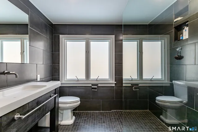 a bathroom with a toilet sink a mirror and window