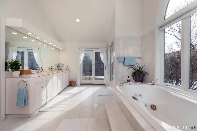 a spacious bathroom with a tub double sink and mirror