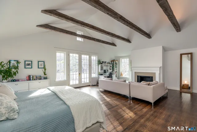 a large white bed sitting in a spacious bedroom next to a window