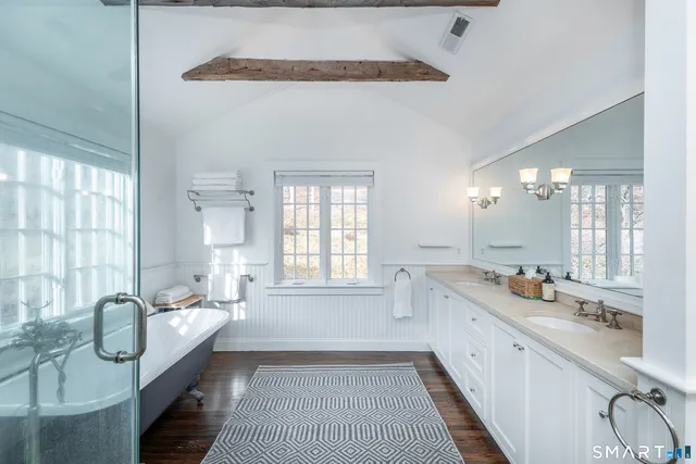 a large bathroom with a granite countertop tub a double vanity sink a window and a shower