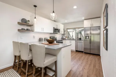 a kitchen with stainless steel appliances granite countertop a sink a stove a refrigerator and island with wooden floor