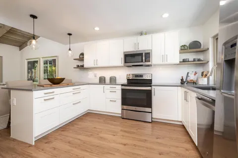 a kitchen with stainless steel appliances a stove a sink and white cabinets