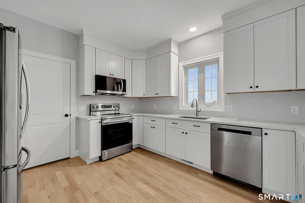 a view of an empty room with wooden floor and window