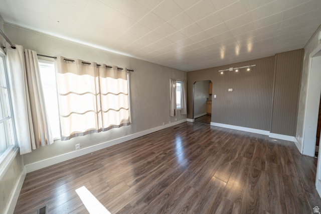 331 North 4th East Price, UT 84501 - Photo 2 of 7 Wood-finish flooring, two large windows, track lighting fixture, beadboard accent wall, and a textured ceiling