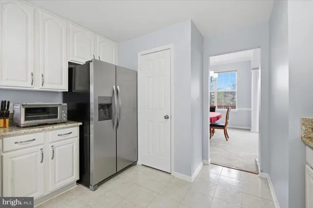 a kitchen with white cabinets and refrigerator