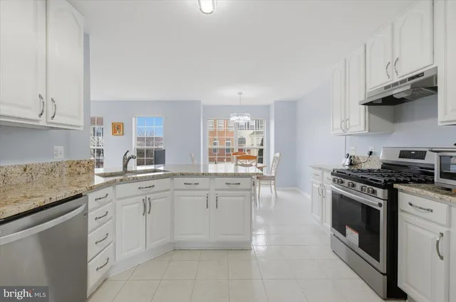 a kitchen with granite countertop white cabinets and stainless steel appliances
