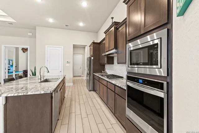 a large kitchen with granite countertop a stove and cabinets