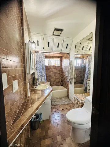 a bathroom with a granite countertop sink a toilet a mirror and shower