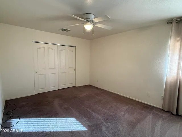 an empty room with a ceiling fan and wooden floor
