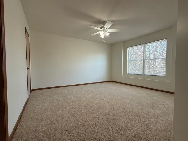 an empty room with windows and fan
