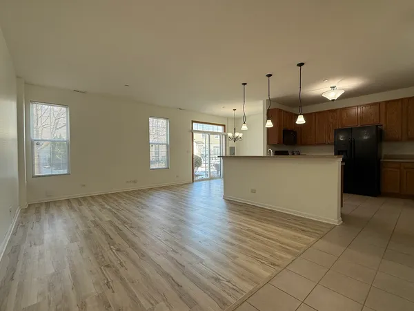 an empty room with wooden floor and a kitchen