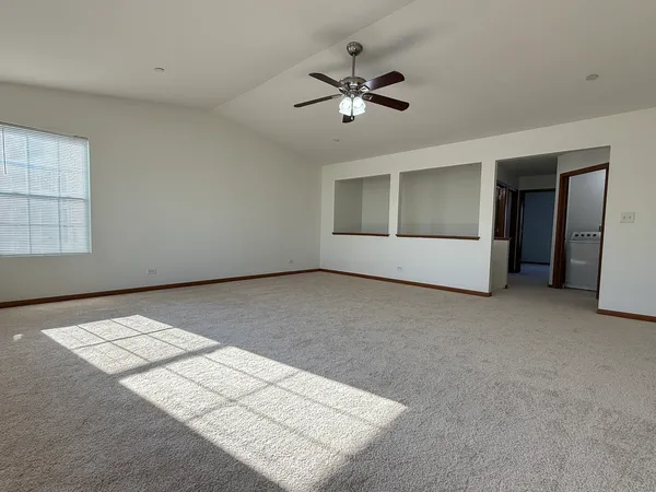 an empty room with windows and fan