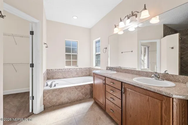 a spacious bathroom with a granite countertop sink a large mirror and a bathtub