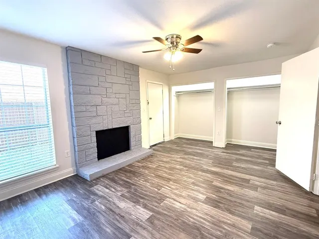 an empty room with wooden floor a ceiling fan and a window