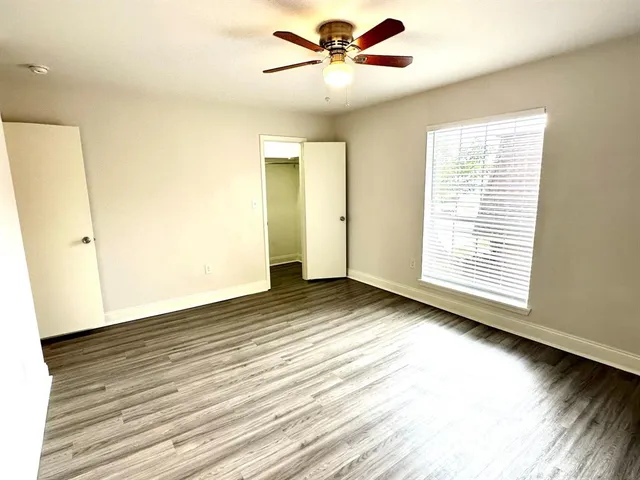 a view of a room with wooden floor and a ceiling fan