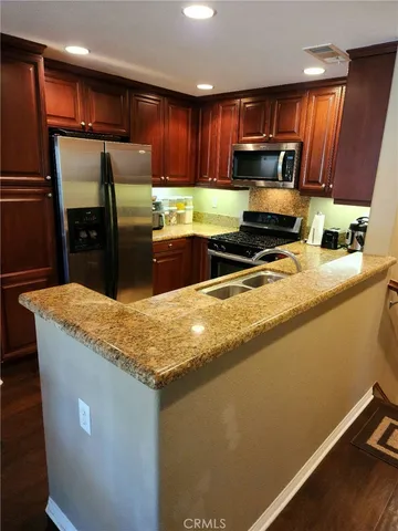 a kitchen with stainless steel appliances granite countertop a sink refrigerator and microwave