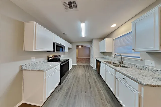 a large kitchen with stainless steel appliances granite countertop a lot of counter space and wooden floor