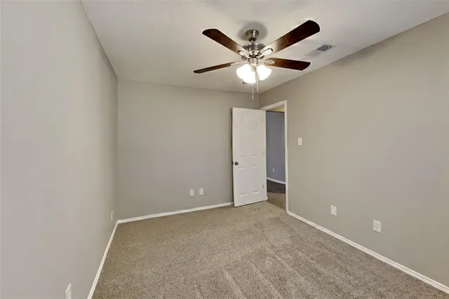 an empty room with a chandelier fan and windows
