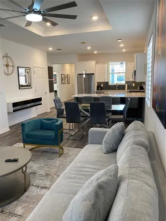 a living room with furniture kitchen view and a chandelier