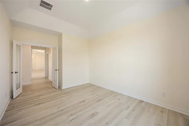 a view of an empty room with wooden floor and closet