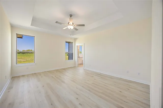 an empty room with wooden floor fan and windows